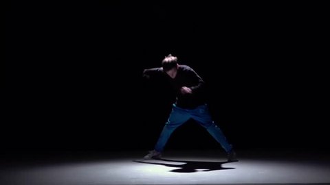Cool breakdance style dancer goes on dance, on black, shadow, slow motion
