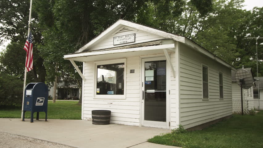 Small town post office exterior with American Flag at half-mast.