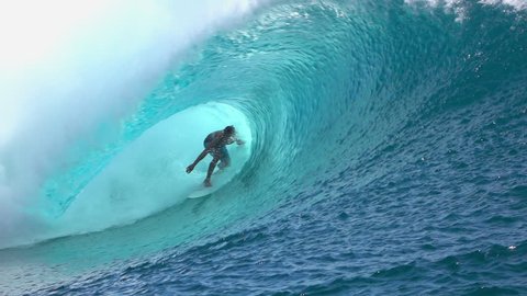 SLOW MOTION: Cheerful extreme pro surfer surfing big tube barrel wave Teahupoo in crystal clear Pacific ocean in sunny Tahiti island