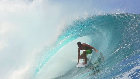 SLOW MOTION CLOSE UP: Cheerful extreme pro surfer surfing big tube barrel wave Teahupoo in crystal clear Pacific ocean in sunny Tahiti island
