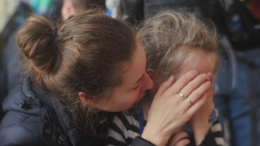 Mom Kisses a Kid, Forehead Kiss, Girl Stops Crying, Mom is Going to Lead a Girl Away, Takes Her Hand, Little Blonde Girl is Crying, Talking Something, Tears Are Coming Down, Wet Face, Kid in Striped | Shutterstock HD Video #15150646