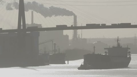 Industrial landscape in smog  with bridge, pipes with steam and tug and container ship silhouette
