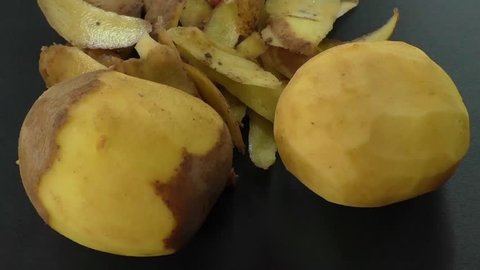 Peeled potatoes and potato peel on the black background 
