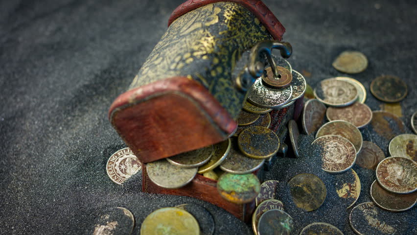 Old casket and old coins on a sand background close up rotation.