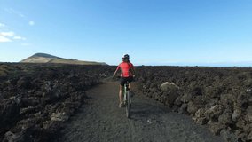 Mountain biking woman cycling on MTB Bike Trail. Sports woman female cyclist riding bicycle in nature living healthy lifestyle. ACTION CAMERA. Lanzarote, Canary Islands, Spain.
