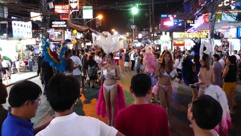 THAILAND, PHUKET ISLAND, PATONG 23. OCTOBER 2015;Ladyboys in garish costume standing on the Bangla Road and trying to collect customers for show.Tourists walking, night life, people traffic. 4K
