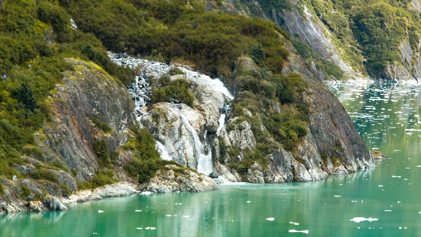 Scenic Waterfalls on the Shores of Tracy Arm Fjord Alaska with Water Rushing Down from the Mountain Tops into the Channel