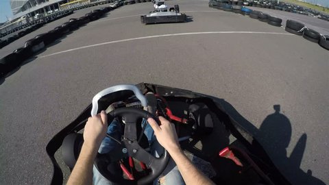 two drivers drive go kart and overtaking on outdoor track, camera is attached to the helmet, Man drives go kart on track, Karting filmed from the driver's view