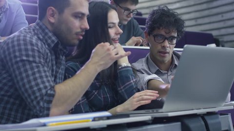 Group of female and male students are sitting in a college classroom and looking at a laptop computer. Shot on RED Cinema Camera in 4K (UHD). Stock Video