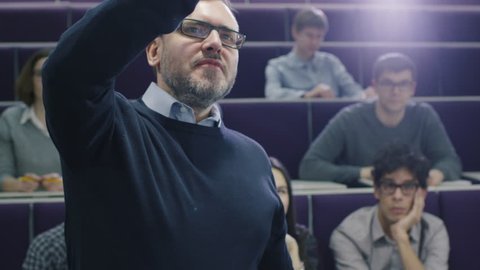 College professor is teaching a class of multi-ethnic students while pointing the desk with a marker. Shot on RED Cinema Camera in 4K (UHD).