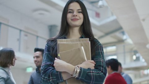 Portrait of a young pretty brunette student girl in an high school hallway. Shot on RED Cinema Camera in 4K (UHD).