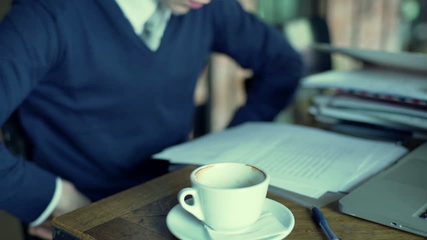 Businessman sitting at the table and reading documents, steadycam shot
