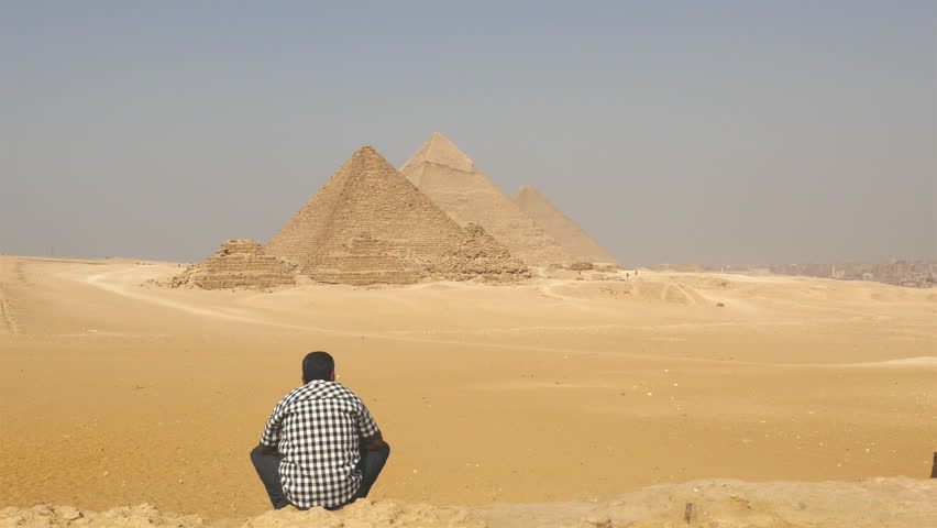 Egyptian sitting in front of The Great Pyramids of Giza - Egypt