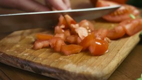 Close-up footage of female hands cutting a tomato on a wooden board,woman cooks a salad. 
