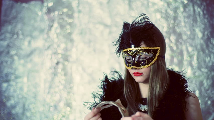 Woman wearing black, carnival mask and looking thoughtful
