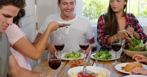 Happy friends having healthy lunch with wine in slow motion