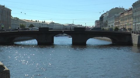 The bridge on the river Fontanka in St. Petersburg with a drive on it with cars and passing under the bridge of the ship.