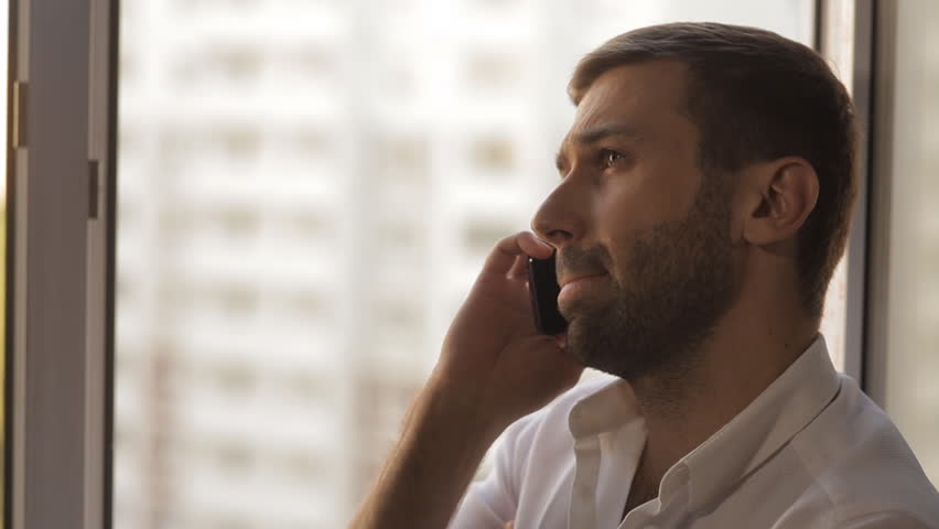 A man in a white shirt speaks on a mobile phone | Shutterstock HD Video #15218035