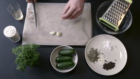 Male Cook Grate Garlic, Glass Bowl, Three Cucumber, Dill, Olive Oil, Spices, Cream, Sour Cream, Mayonnaise, Sauce Ingredients, Recipe, Cooking, Video, Food, Products on the Black Table