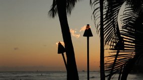 Three tiki torch flames blowing in the wind shortly after sunset on Waikiki Beach in Honolulu on Oahu, Hawaii.