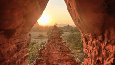 Sunset timelapse in Bagan, Myanmar. Dolly sliding along the walls of stupa/pagoda, and coming out of the brick door. Fast motion video of moving clouds.