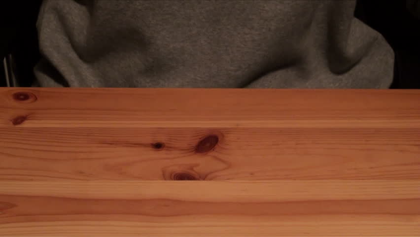 Woman typing on a smartphone, black background, wood table. Woman dressed in a gray sweatshirt is writing an email or a text message on your smartphone-Adrian