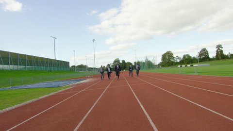 4K Group of competitive businessmen racing to the finish line at running track