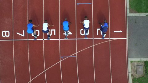 4K Aerial view of track athletes at running track, competing in a race