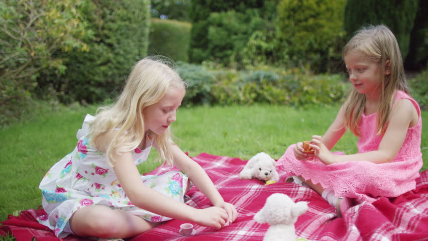 4K 2 little girls having a tea party with their toys in the garden Shutters...