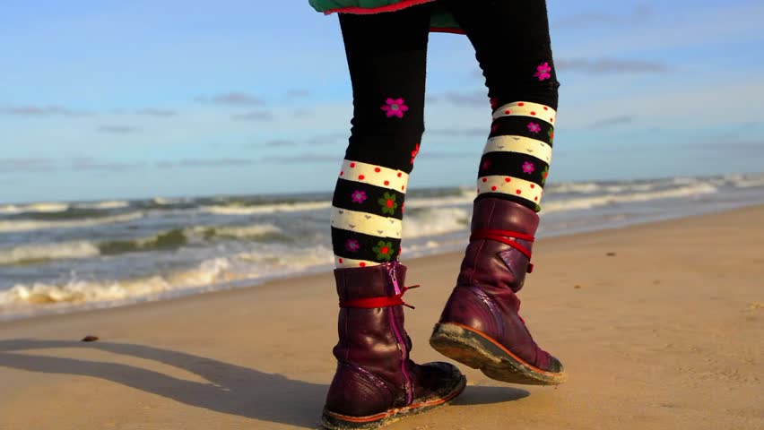 Little beautiful girl walks in autumn day along the shore of the Baltic Sea area in Leba, Poland.