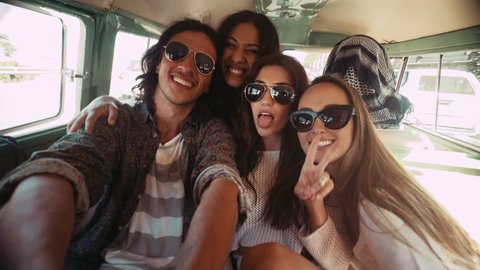 Three happy hipster young women taking selfie sitting in a vintage van during a summer road trip