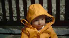Caucasian Baby Boy watches Bubbles fall around him while he wears a yellow rain jacket 