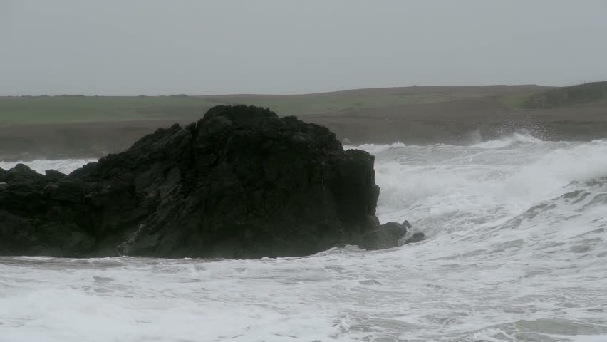 Storm Waves Crashing On Large Rocks As The Waves Hit Shore. Slow motion footage of large storm waves crashing on rocky cliffs.