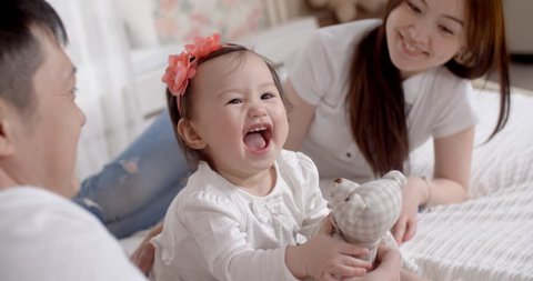 family idyll,a young Asian family with two daughters, a fun play at home on the bed with the baby 1 year, slow motion