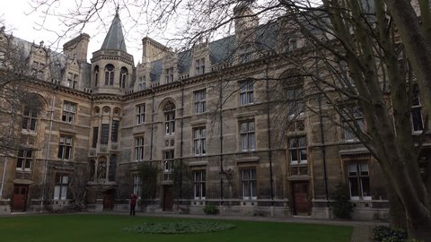 CAMBRIDGE, ENGLAND - MAR 2016: Cambridge University England courtyard woman walking. Founded in 1209, one of the top five universities in the world, 30,000 students. Technology, medical, bioscience.