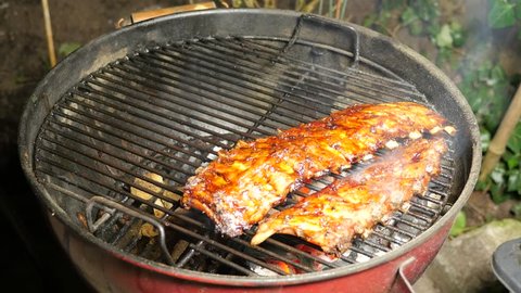 BBQ spicy marinated and smoked pork spareribs on the hot charcoal grill with bright flames