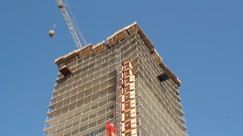 Condo construction. Timelapse. Timelapse of condominium being built in Toronto, Ontario, Canada. Tower crane raises concrete bucket and swings around. Elevator goes up.  