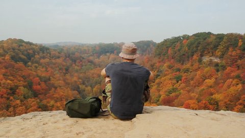 Hikers reward. Man rests after hiking to top of cliffs. View of autumn forest below. Dundas, Ontario, Canada. 