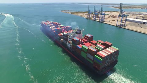 AERIAL: Container ship, loaded with shipping freight containers leaving port, freight transportation