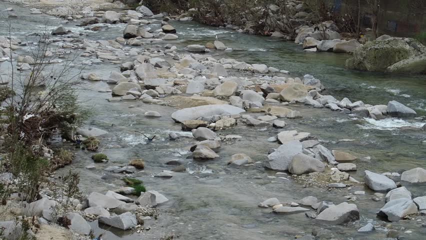 Kosynthos river water running on a rocky river bed by the city of Xanthi, Greece on a cloudy day 