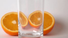 Two orange halves and orange juice being poured into glass. Super slow motion video