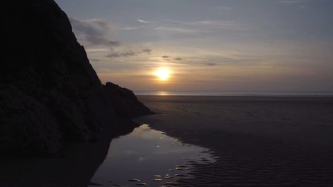 The sun is setting behind the perfect fine golden sandy beach at low tide.