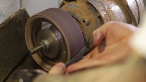 Shoemaker repairing sole footwear in the grinder machine