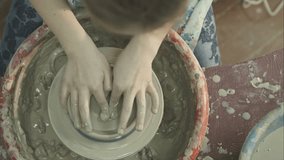 Hands of a woman creating a clay jar on a potter's wheel. RAW video record.