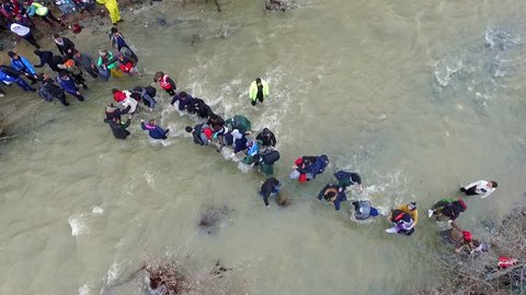 Idomeni, Greece - March 14, 2016: Hundreds of migrants and refugees cross a river, north of Idomeni, Greece, attempting to reach Macedonia on a route that would bypass the border fence