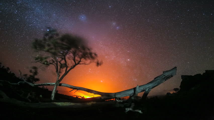 4K trees with starry night sky and active volcano fire in background time-lapse 