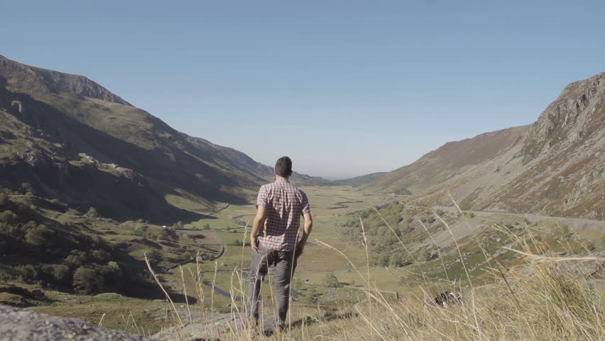 Hiker Taking A Photograph Overlooking Pretty Valley. A shot of a tourist hiker taking a photo on his smartphone of a undisturbed Welsh valley.