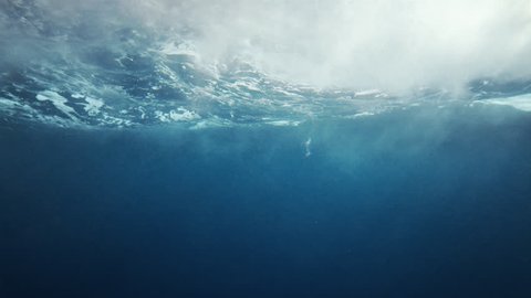 Beautiful underwater sea scene view with natural light rays, shining through the water's glittering and moving surface, caustics, bubbles, and foam, perfect for background and digital composition