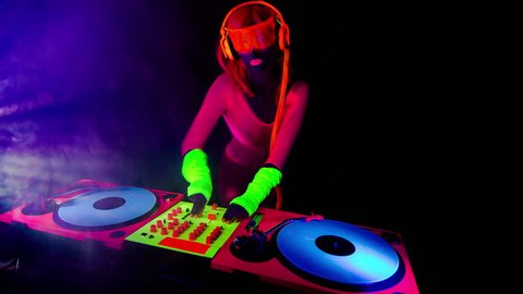 4k sexy female DJ mixes in a club in UV fluorescent costume. stylish,  cool and unique clip for events, parties and shows