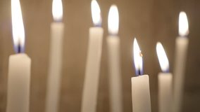 Close-up votive white candles burning slowly in the church in act oft Christian prayer slow-mo 1080p HD video - Slow motion burning prayer candle made of wax flame closeup 1920X1080 FullHD footage